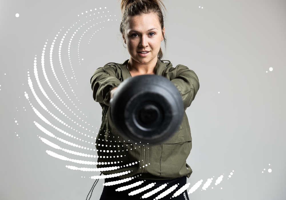 Bee Fit coach, Shelby doing a kettlebell swing. She is facing the camera and the bottom of the kettlebell is facing the camera.